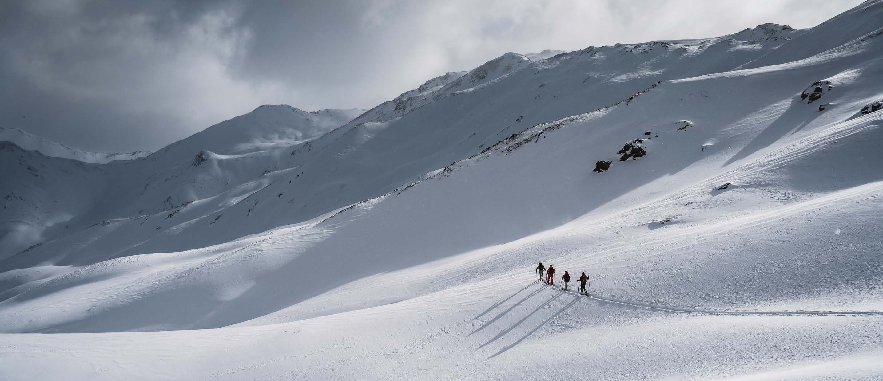 Skitourengruppe steigt in einer Reihe einen weiten Hang im Obervinschgau auf