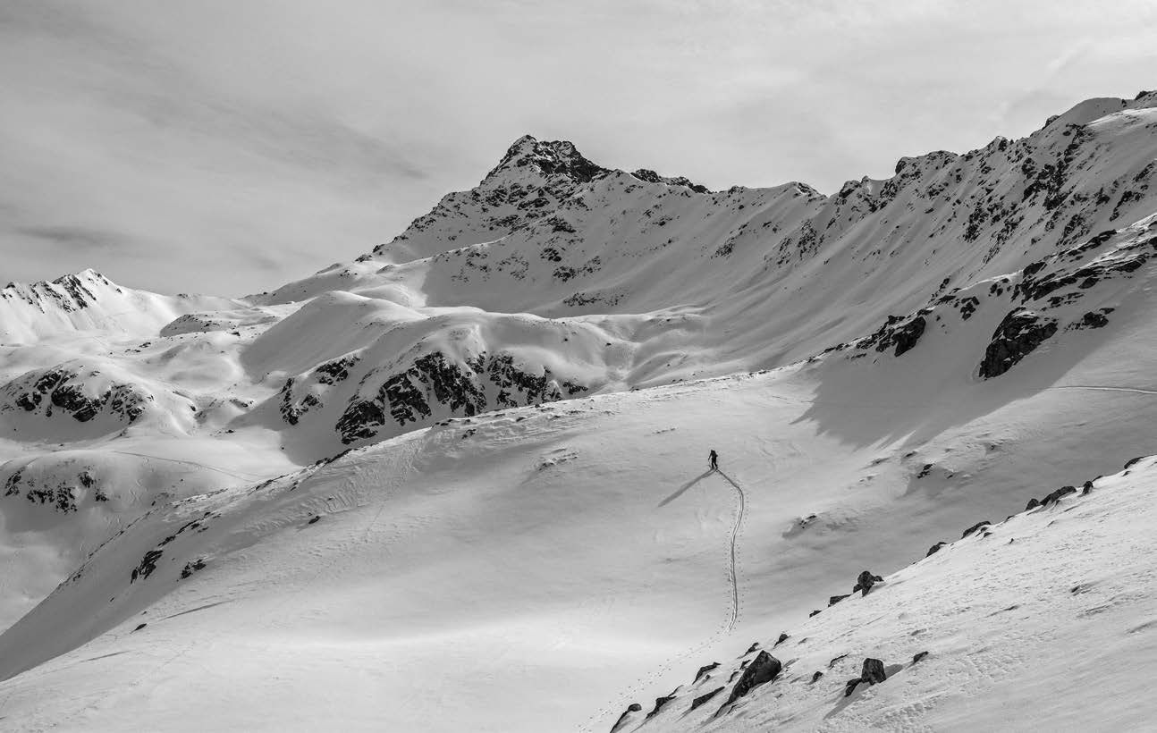 Schwarz-Weiß-Panorama mit Aufstiegsspur durch ein verschneites Hochtal