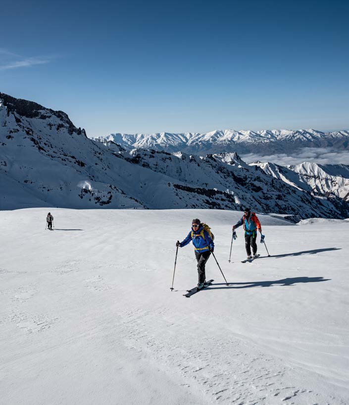 Three ski tourers climbing in front of snow-covered Alborz peaks