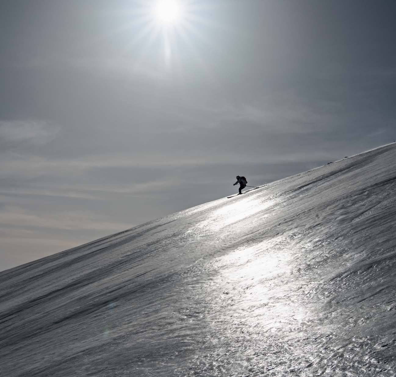 Backlit skier on a glittering icy slope