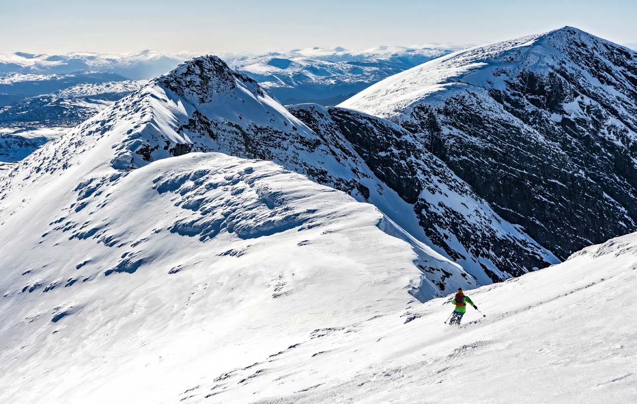 Skifahrer fährt einen weiten Hang zwischen Bergrücken in Rondane ab
