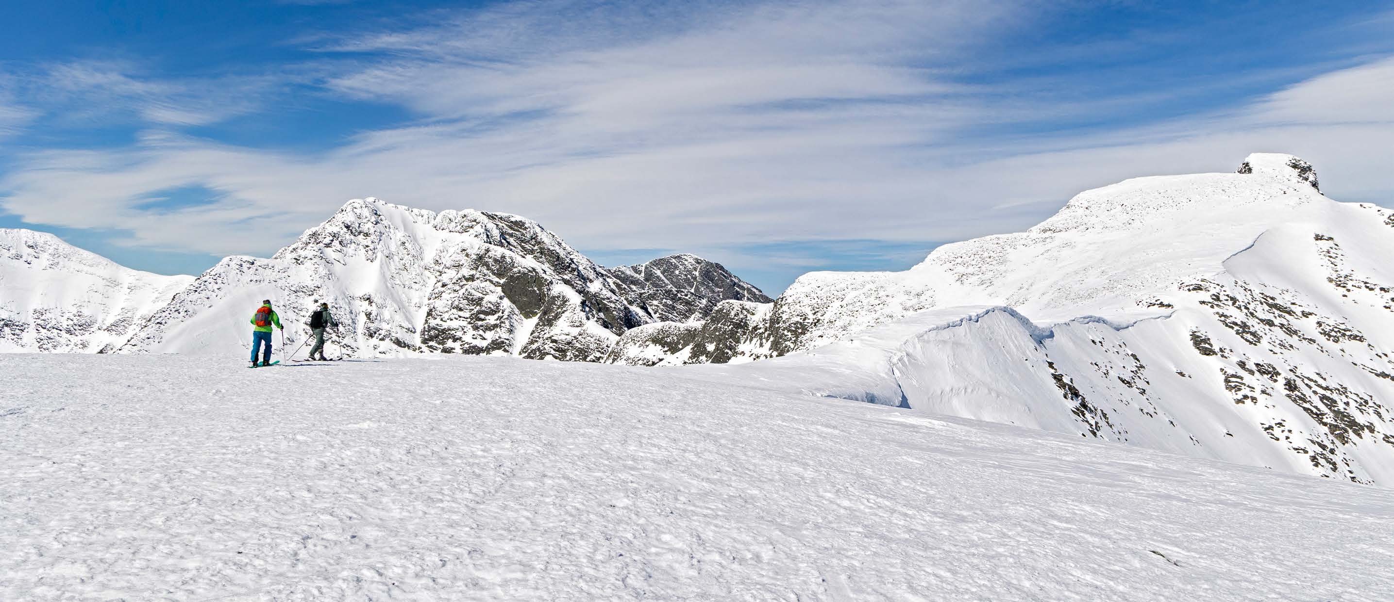 Skitourengeher queren eine weite Schneefläche im Rondane-Nationalpark