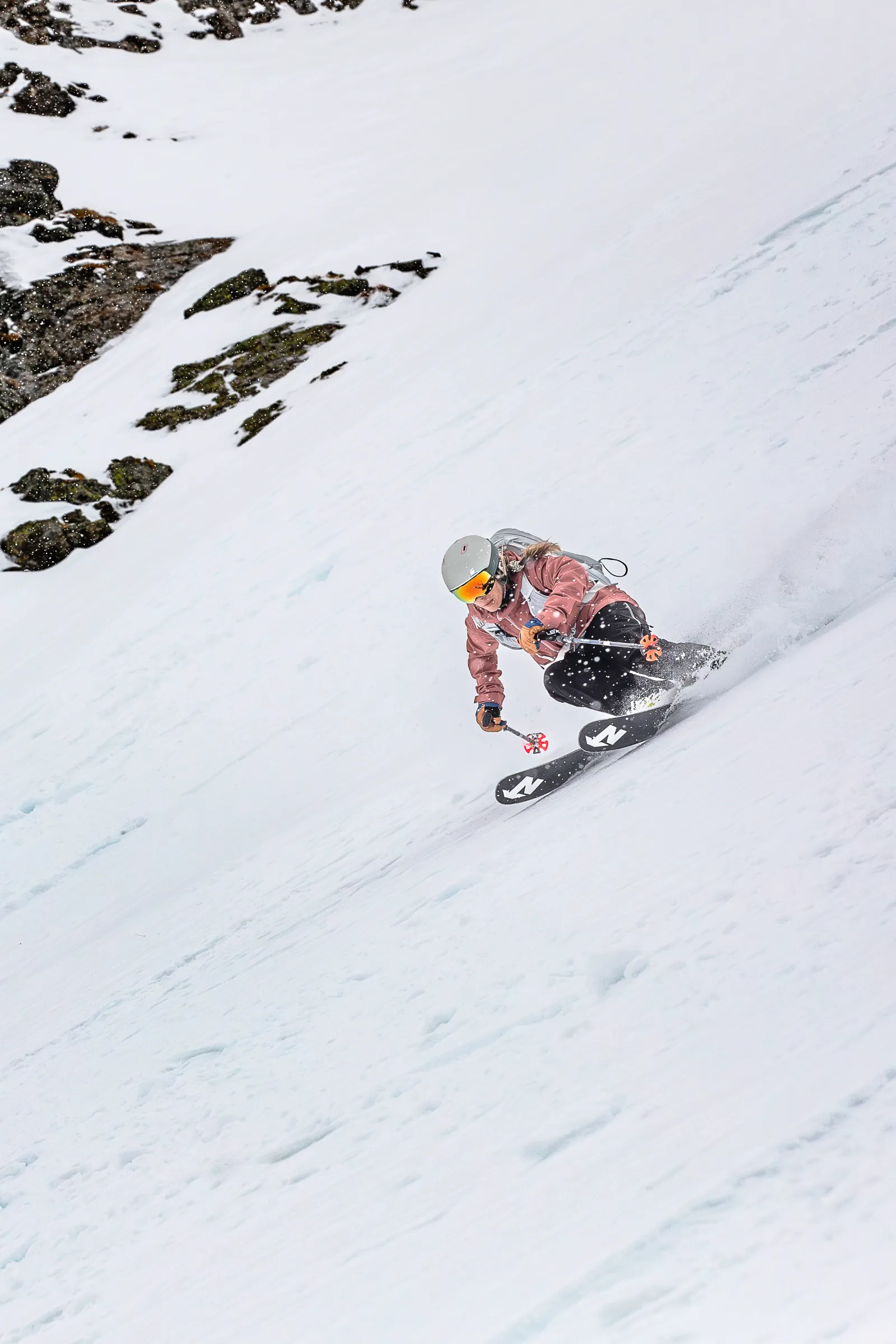 Andrea Limbacher making a freeride turn on a snowy slope below rocky outcrops in Lenzerheide.