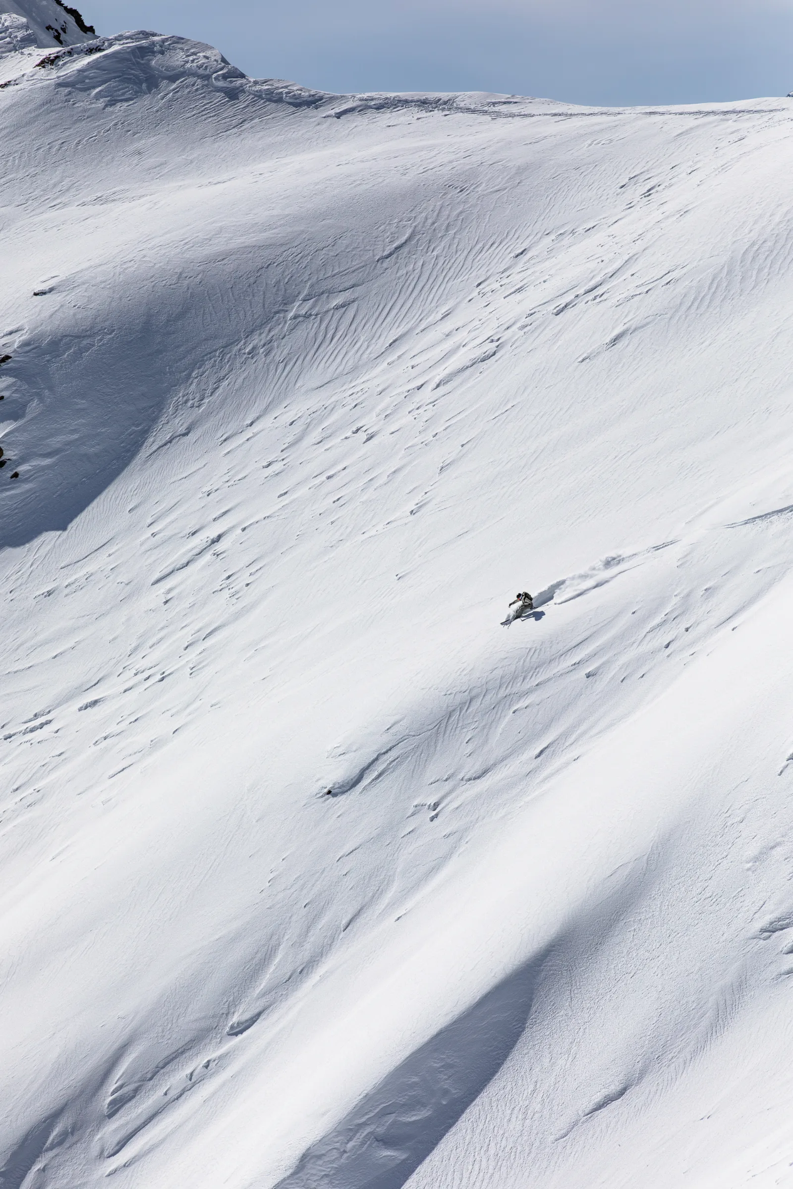 Claudia Kohler makes a turn across a vast, rippled snow slope in Lenzerheide, leaving a plume of snow behind her.