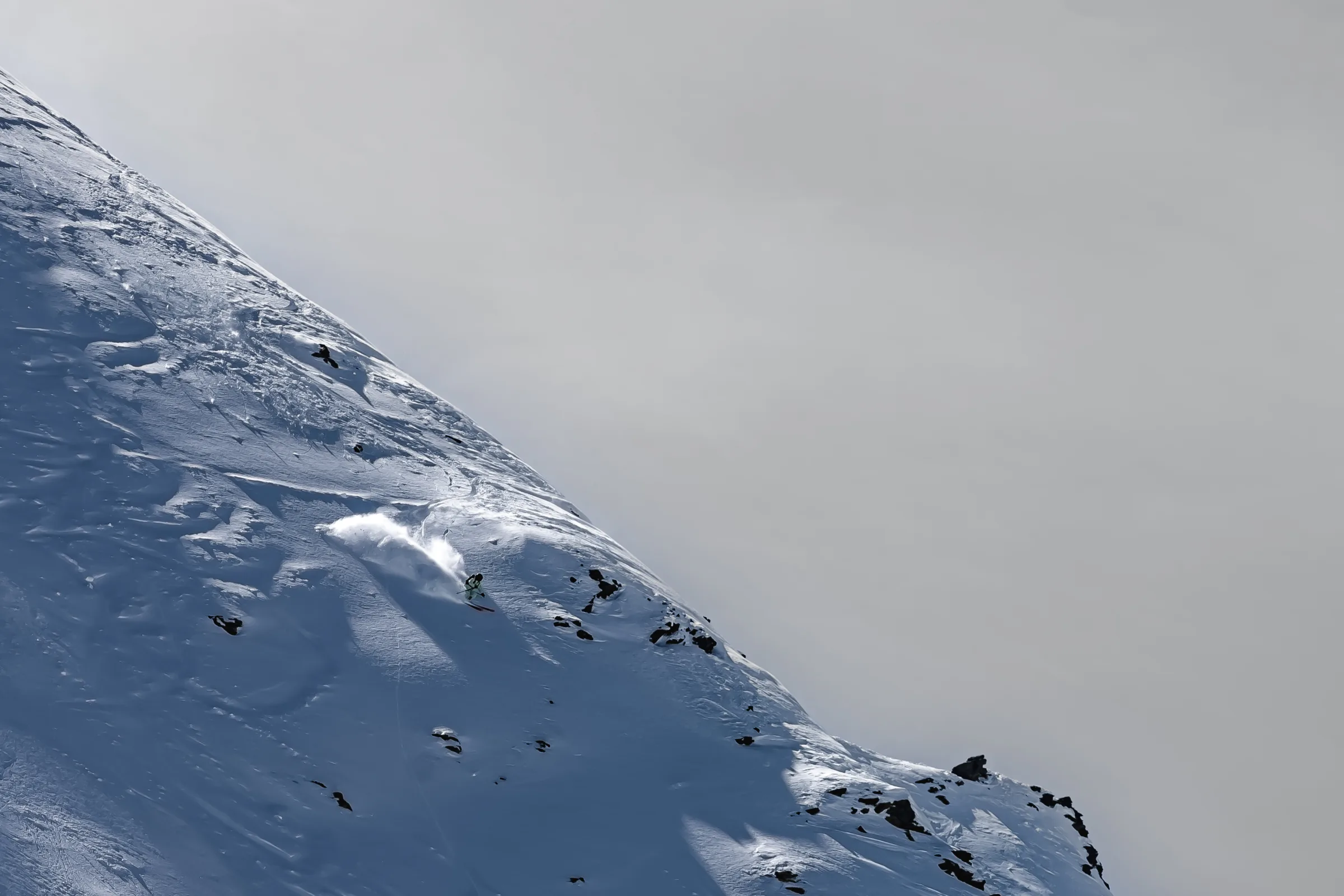 Claudia Kohler turns on a steep, rock-studded snowy slope in Lenzerheide, throwing up a bright plume of snow.