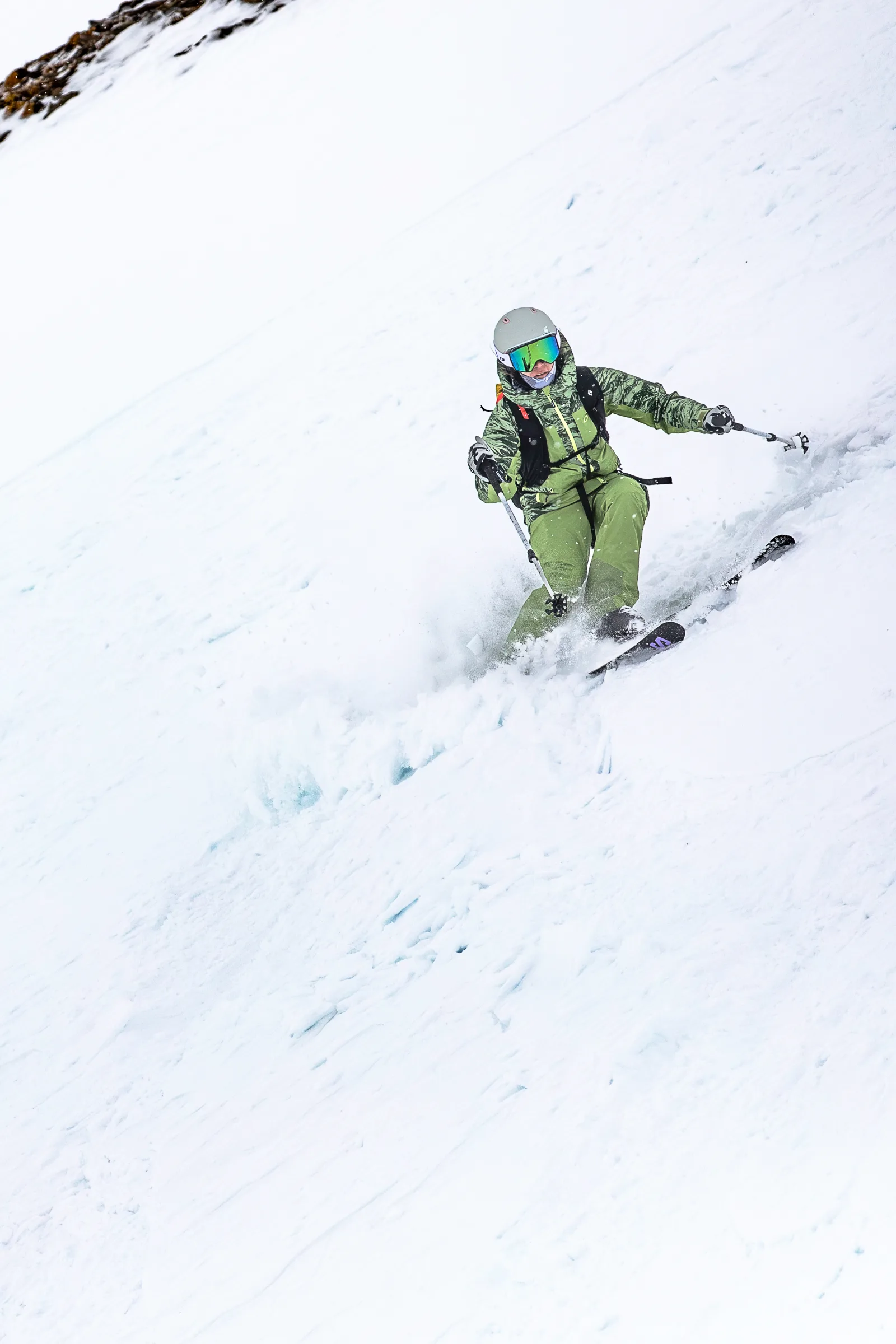 Martina Wengenmeir zieht mit seitlich gehaltenen Skistöcken einen Schwung durch den steilen Schneehang, während Schnee um ihre Ski aufwirbelt.