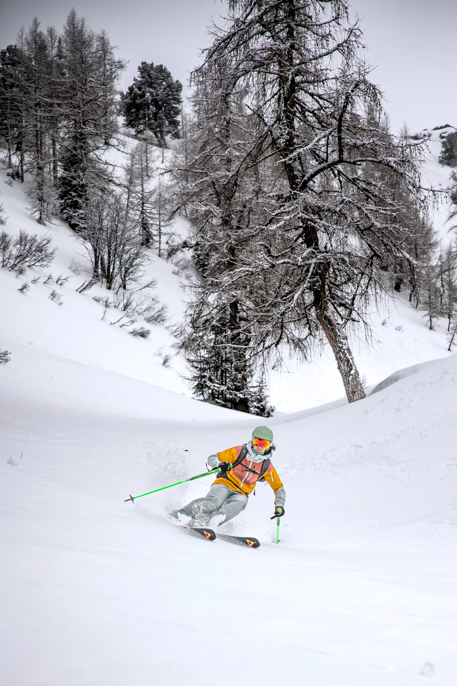 Sabine Speidel skis through deep snow among snow-covered trees in Gastein, holding bright green poles.