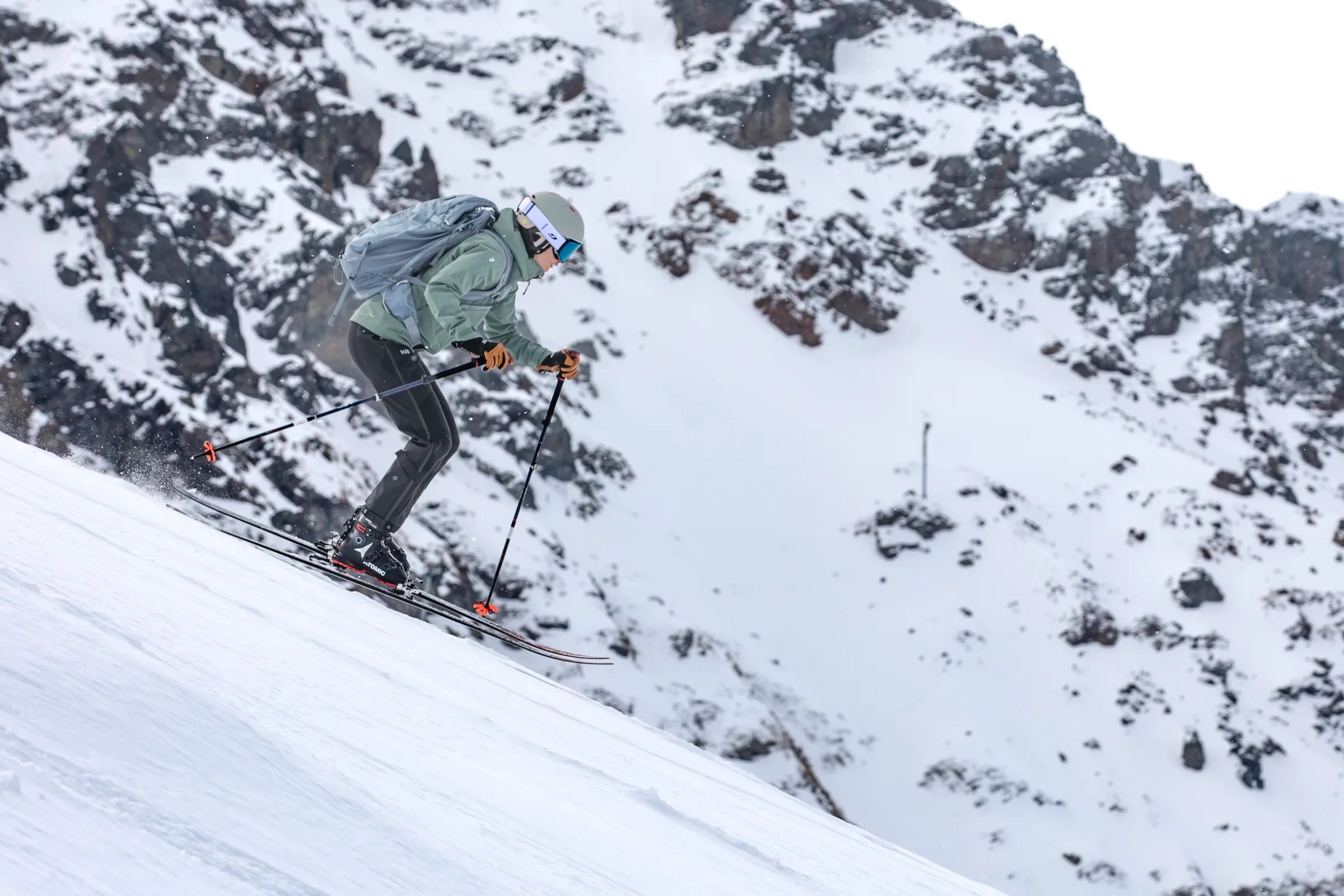 Sabrina Stickl fährt mit gebeugten Knien und vorgestreckten Stöcken einen Schneehang in Lenzerheide hinab, hinter ihr ragen felsige Bergflanken auf.
