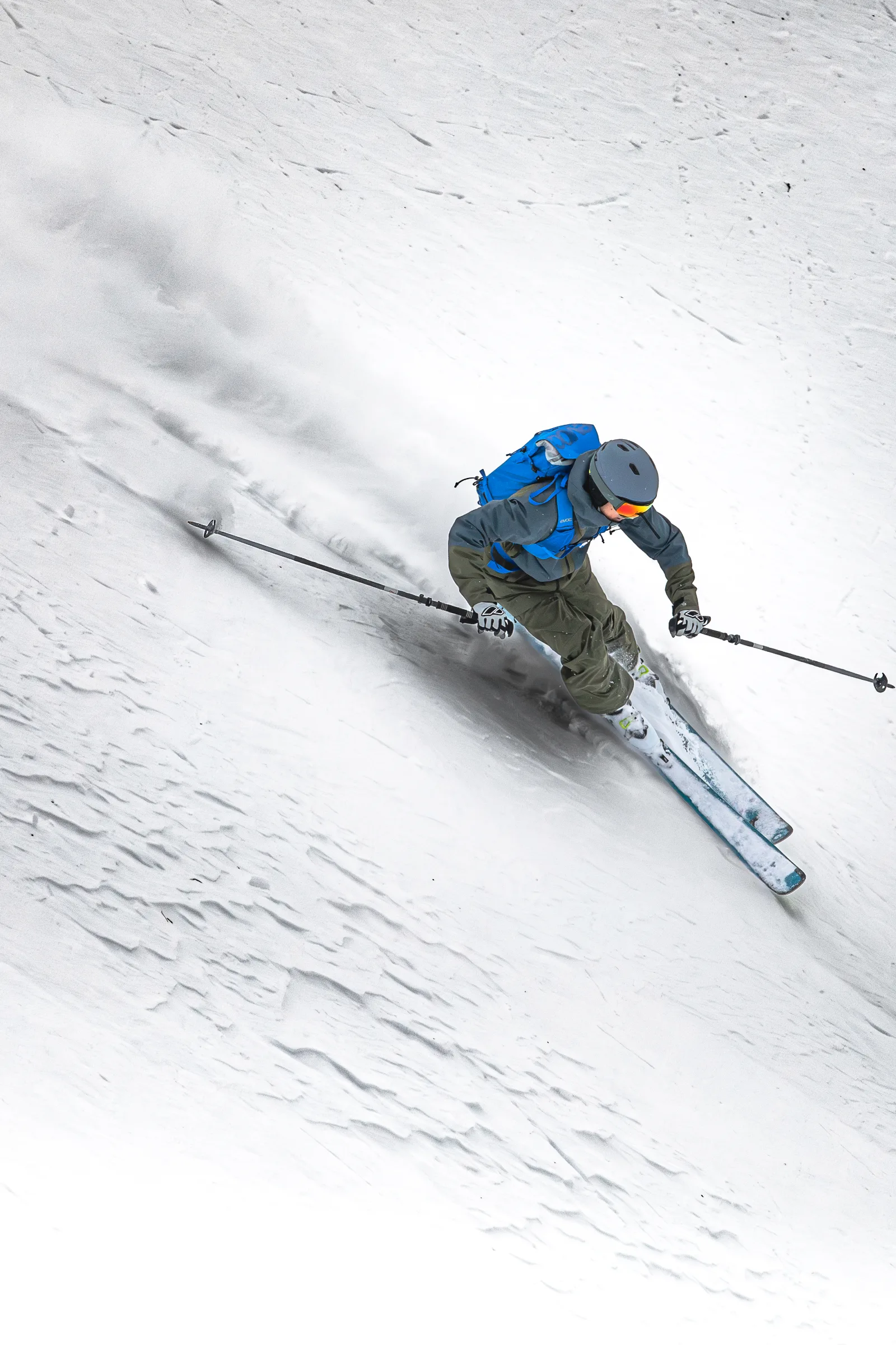 Seen from above, Valentin Rapp turns on parallel skis with his poles held wide across a textured snowy slope.